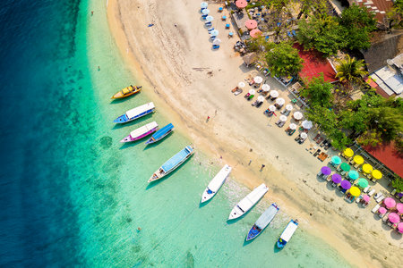 Top down view of colorful sunshades and tourist boats on a tropical beachの写真素材