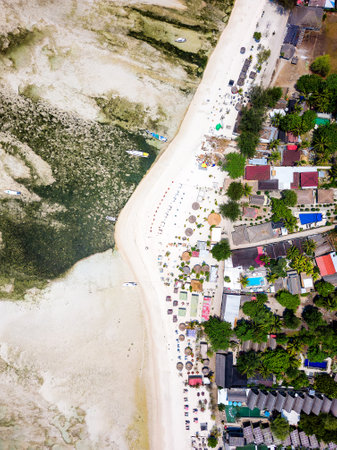 Top down aerial view of various sunshades and resorts along a tropical beach at low tideの写真素材