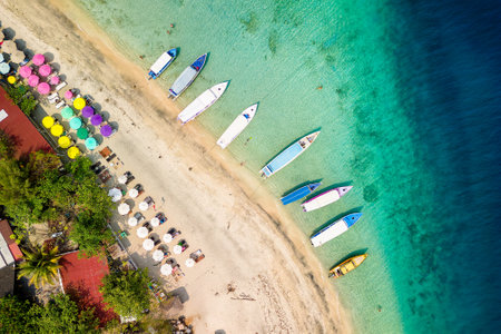 Top down view of colorful sunshades and tourist boats on a tropical beachの写真素材