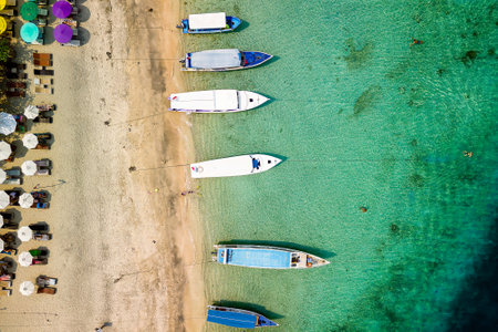 Birds eye view of colorful sun umbrellas and boats on a small, warm tropical beachの写真素材