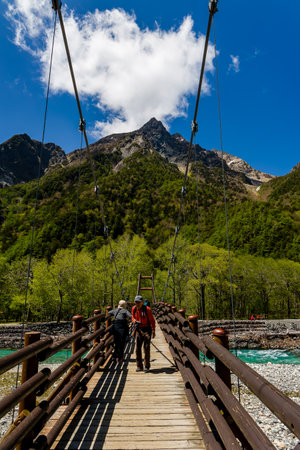 KAMIKOCHI, JAPAN - MAY 24 2023: Hikers crossing the Myojin suspension bridge over the Azusa River in Kamikochi, Nagano, Japanのeditorial素材