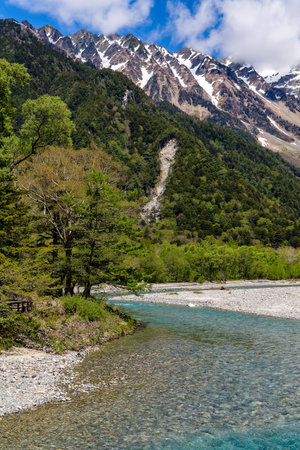 Fast flowing clear river running through a forest and mountainsの写真素材