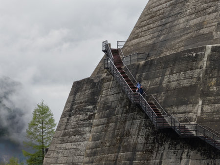 KUROBE DAM, JAPAN - MAY 26 2023: Tourists braving stormy skies and rain on top of the Kurobe Dam,...