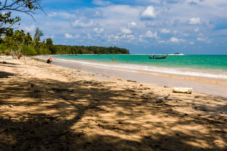 KHAO LAK, THAILAND - APRIL 04 2024:- A volunteer picking up plastic bottles and other trash washed up by the ocean onto a tropial beach in Thailandのeditorial素材