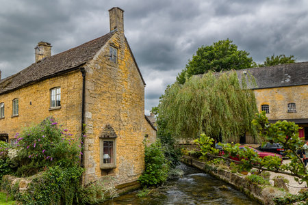 BOURTON-ON-THE-WATER, ENGLAND - JULY 24 2024: Tourists in the ancient traditional Cotswolds village...