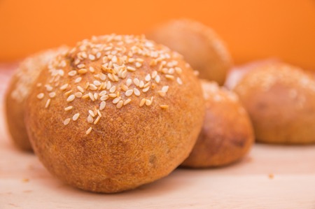 Tasty buns with sesame, on wooden background