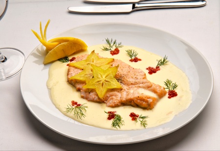 Salmon fish fried with butter sauce decorated with red caviar on a plateの写真素材