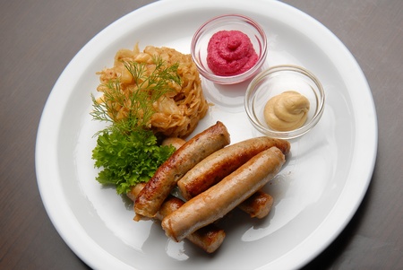 Grilled sausages with sauerkraut and sauce on a plateの写真素材