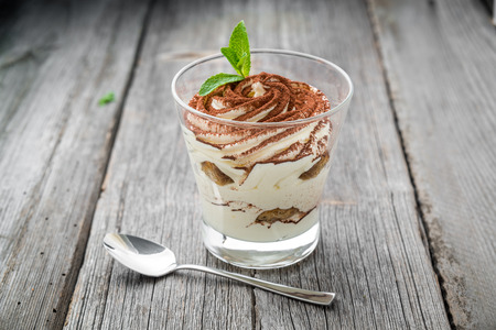 Traditional Italian dessert tiramisu in a glass. On a wooden tableの写真素材