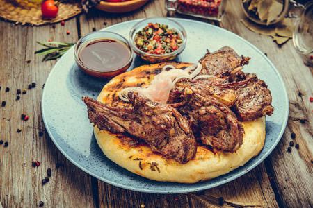 two pieces of of grilled pork with herbs on a paper on an old table top view horizontal close-upの写真素材