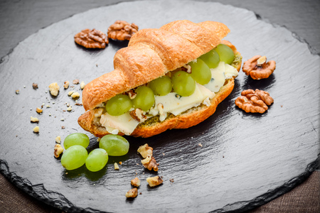 Freshly baked croissants filled with brie cheese and grapes, on a stone tableの写真素材