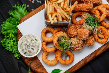 Take away food mozzarella balls, squid rings, onion rings, french fries, chicken nuggets and sauceの写真素材