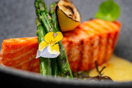 Grilled salmon steak with cheese sauce and asparagusの写真素材