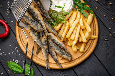 Small fried fish and french fries at an seaside restaurant. Fried anchovies. Photo for the...