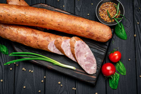 Smoked homemade sausage ring. Sausage on a black background. Photo for the menuの写真素材