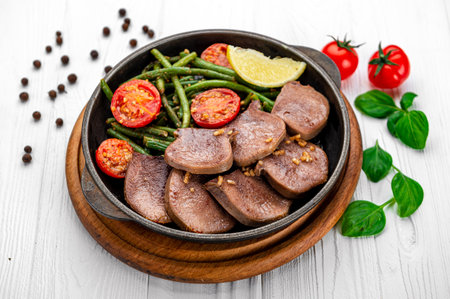 Fried beef tongue with green beans and tomatoes in a pan. Serving food in a restaurant. Photo for the menuの写真素材