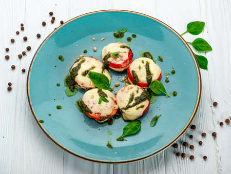 Baked tomatoes with mozzarella cheese and pesto sauce. Vegetarian food.の写真素材