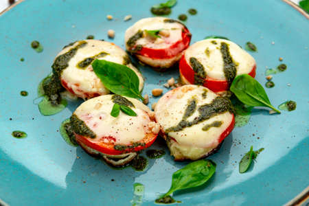 Baked tomatoes with mozzarella cheese and pesto sauce. Vegetarian food.の写真素材