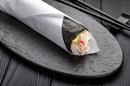 Hand roll with crab, avocado and cream cheese on a dark background.. Asian cuisine. Photo for the menu.の写真素材