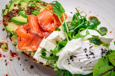 Bruschetta with sliced avocado, feta cheese, pesto sauce, poached egg and salted salmon. Healthy and wholesome food. Serving food in a restaurant. Photo for the menu.の写真素材