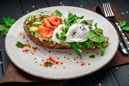 Bruschetta with sliced avocado, feta cheese, pesto sauce, poached egg and salted salmon. Healthy and wholesome food. Serving food in a restaurant. Photo for the menu.の写真素材