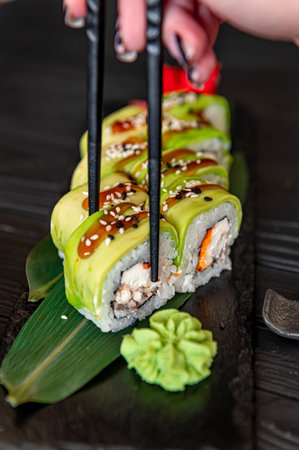 Sushi roll with smoked eel unagi covered by avocado and sesame seeds. Sushi roll with rice, cream cheese, avocado, salmon, sesame. Sushi menu. Japanese kitchen, restaurant.の写真素材