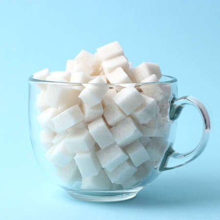 Refined sugar in a glass on a colored background. Diabetes concept, excess sugarの写真素材