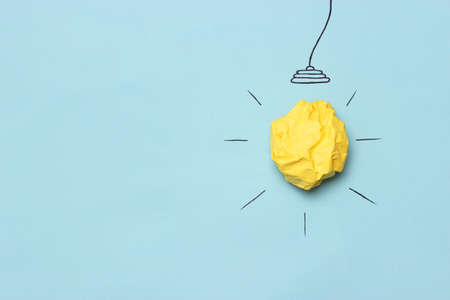 creative concept idea. Painted light bulb with a crumpled paper yellow ball.