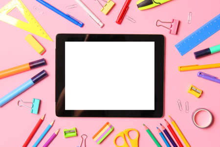 Modern digital tablet and school stationery on a colored background top view.の写真素材