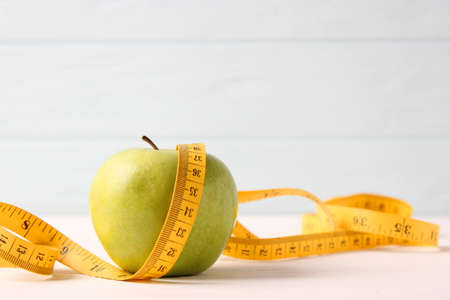 apple and measuring tape close-up on a light backgroundの写真素材