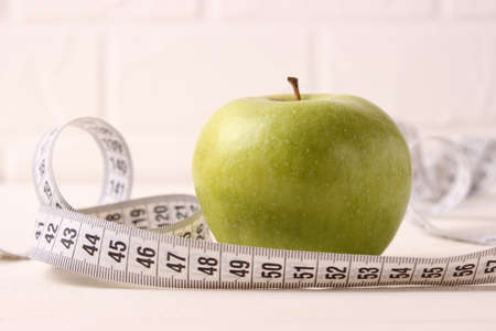 apple and measuring tape close-up on a light backgroundの写真素材