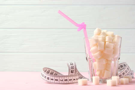 sugar in a glass and measuring tape on a colored background.の写真素材