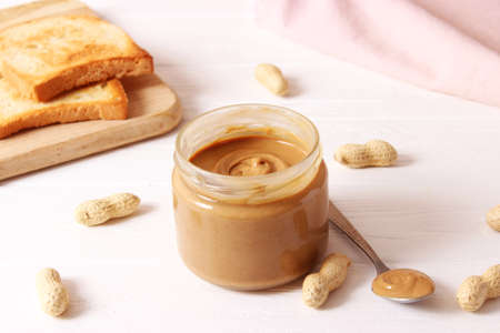 creamy peanut butter and peanuts beans on wooden background top viewの写真素材