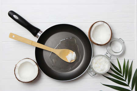 Coconut oil and a frying pan on a wooden table close-up.の写真素材