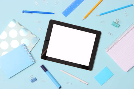 Modern digital tablet and school stationery on a colored background top view.の写真素材