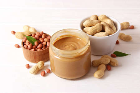 creamy peanut butter and peanuts beans on wooden background top viewの写真素材