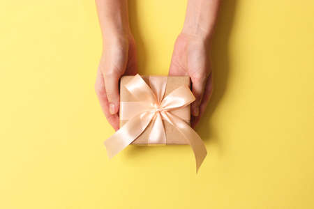 gift in female hands on a colored background with confetti top view.の写真素材
