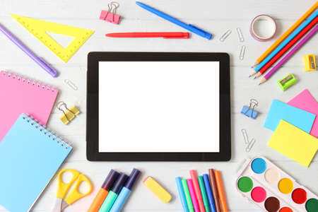 Modern digital tablet and school stationery on a colored background top view.の写真素材