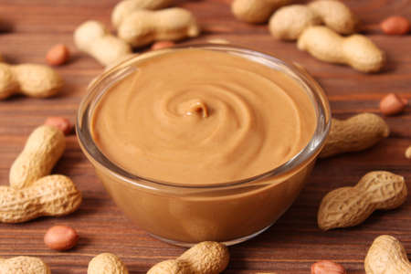 creamy peanut butter and peanuts beans on wooden background top viewの写真素材