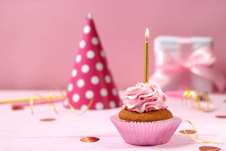 Delicious cupcake with a candle on a colored backgroundの写真素材