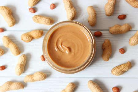 creamy peanut butter and peanuts beans on wooden background top viewの写真素材