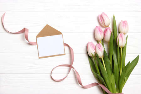 A bouquet of beautiful tulips and a gift on a wooden background top view.の写真素材