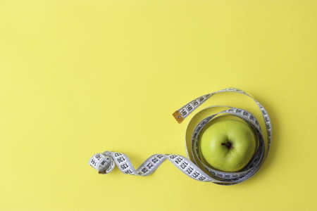 apple and measuring tape on a colored background close-up with place for text.
