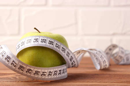 apple and measuring tape close-up on a light background