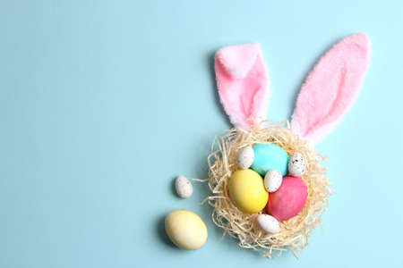 Easter composition of painted eggs and feathers on a colored background.