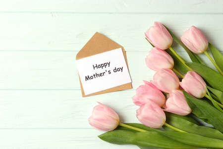 A bouquet of beautiful tulips and a card for text on a wooden background