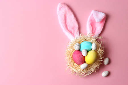 Easter composition of painted eggs and feathers on a colored background.