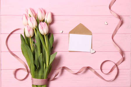 A bouquet of beautiful tulips and a gift on a wooden background top view.の写真素材