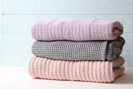 Warm knitted sweaters folded in a stack on a light background close-up.の写真素材