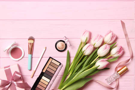 makeup products and beautiful spring flowers on wooden background. Top view.の写真素材